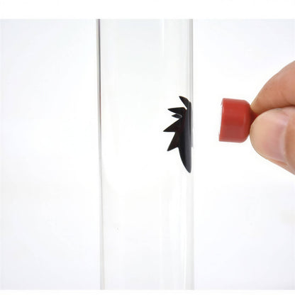Venom symbiote ferrofluid kit with a clear tube and a hand manipulating a red magnet near black fluid.